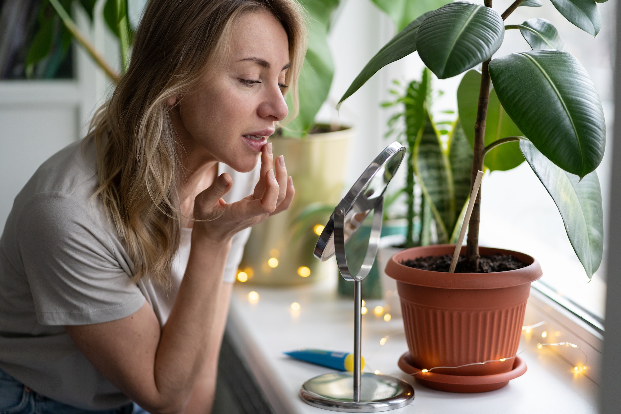 Woman applying moisturizing balm to her lips with her finger to prevent dryness and chapping