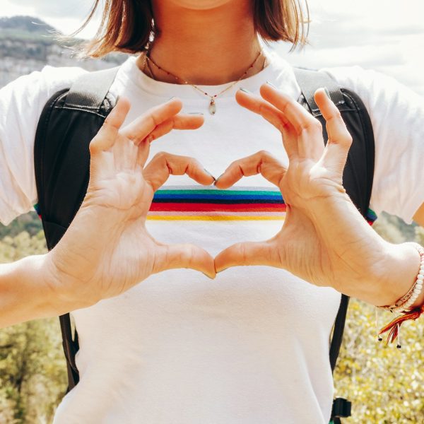 Close up of female hiker hand doing love symbol rainbow